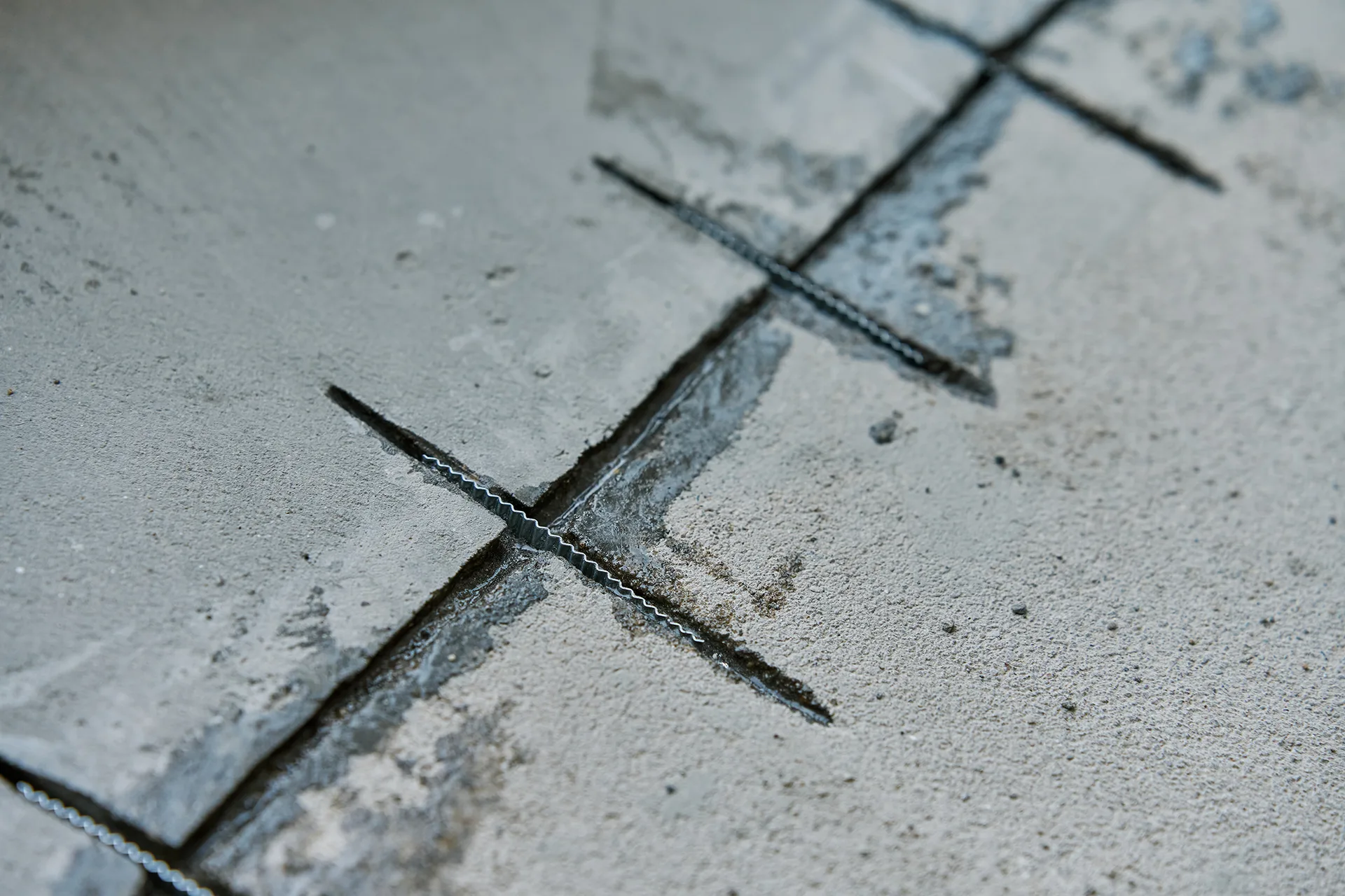 Metal crack stitching staples installed across a concrete crack